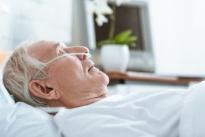 Hombre mayor recostado en un hospital con una cánula nasal.