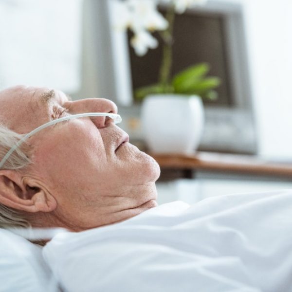 Hombre mayor recostado en un hospital con una cánula nasal.